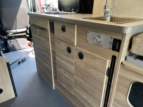 Compact RV rental kitchen area featuring a sink, stovetop, and eco-HOT controls, ideal for on-the-go living.