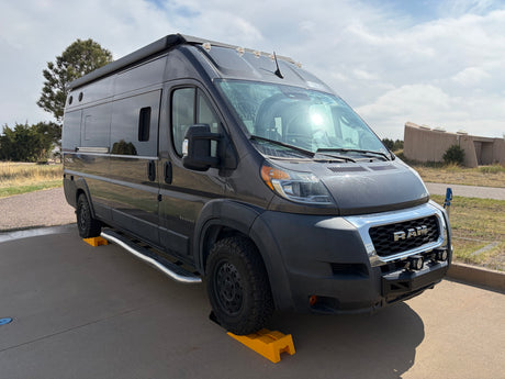 Dark gray Entegra RAM ProMaster RV rental parked on leveling blocks.