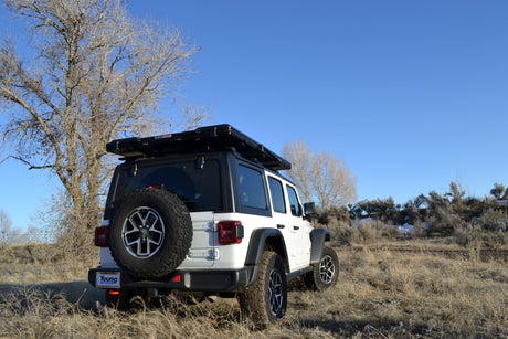 White Jeep Wrangler with a rooftop tent, an ideal RV rental for off-road camping and adventure.
