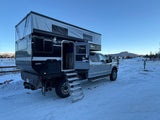 Rugged Four Wheel Hawk+ truck camper RV rental, pop-top extended on a snowy day. Steps deployed for winter adventure.