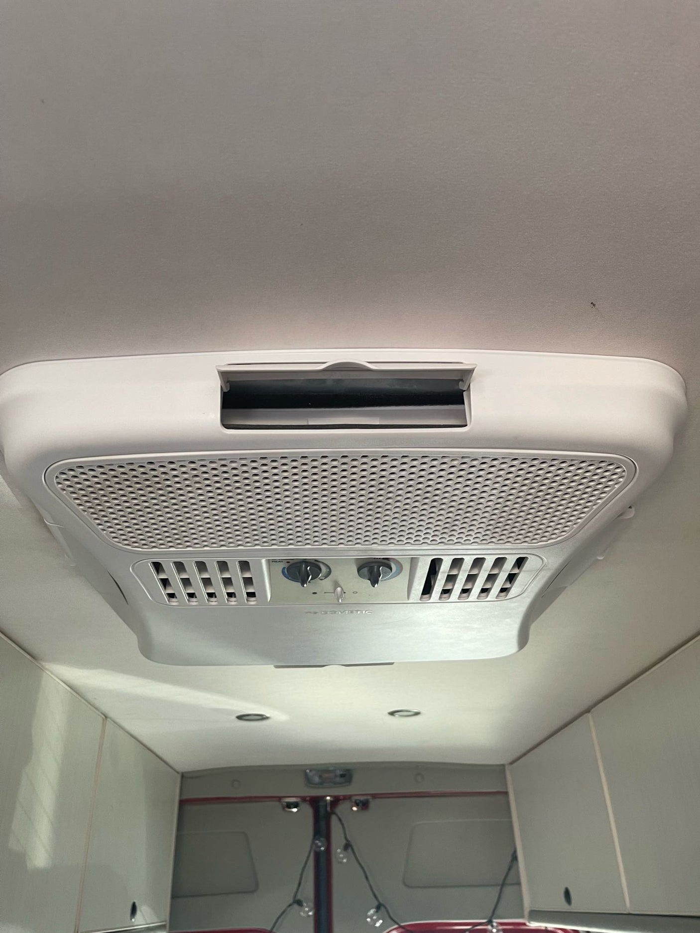A white Dometic air conditioner unit is seen on the ceiling of an RV rental, providing essential climate control.