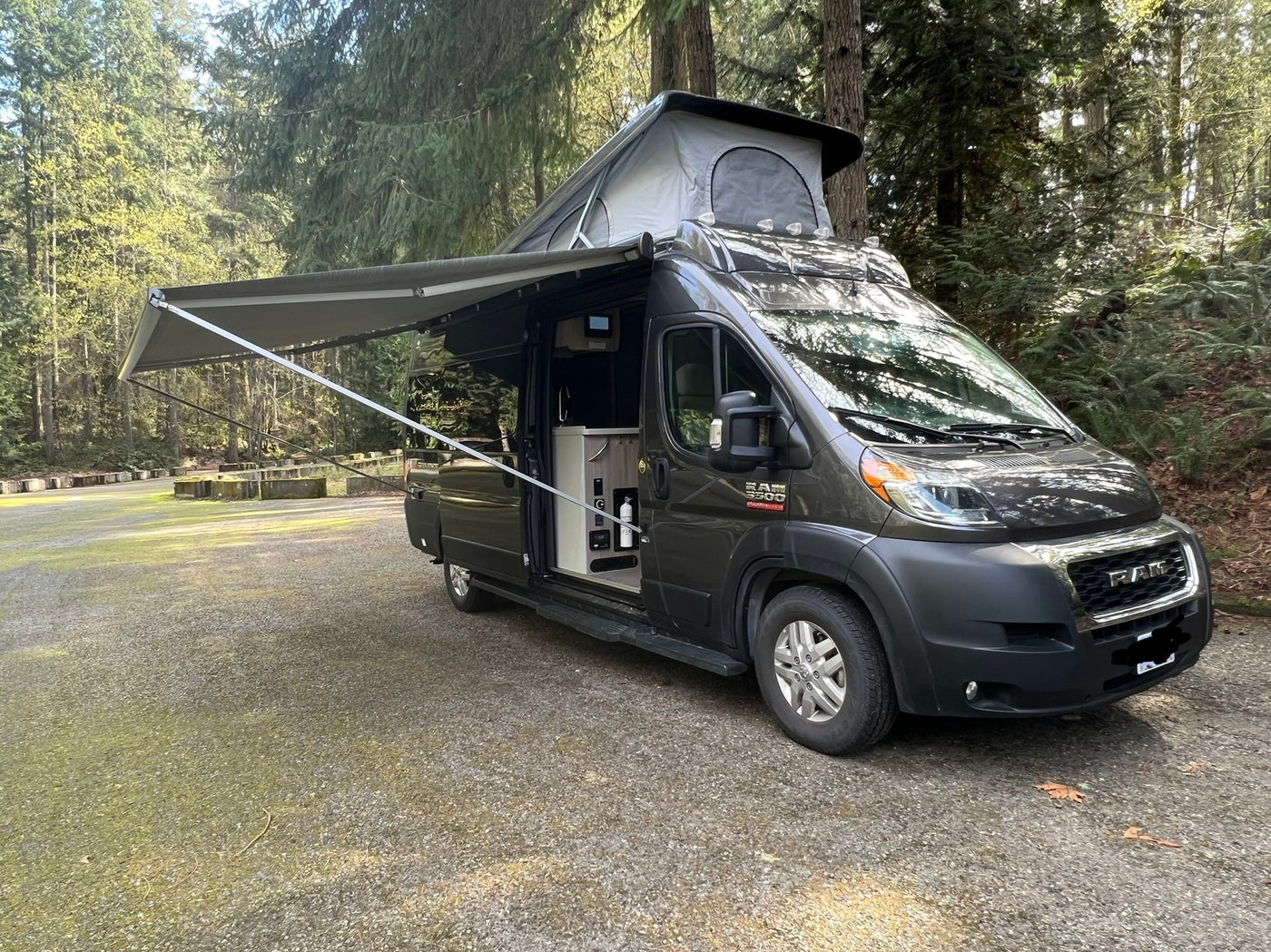 Pop-top RAM camper van, an ideal rv rental, parked with awning extended in a serene forest campground. Explore nature! — photo 2