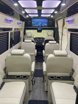 Luxurious RV rental interior: cream leather seating, entertainment screen, stylish lighting, and wood-look flooring.