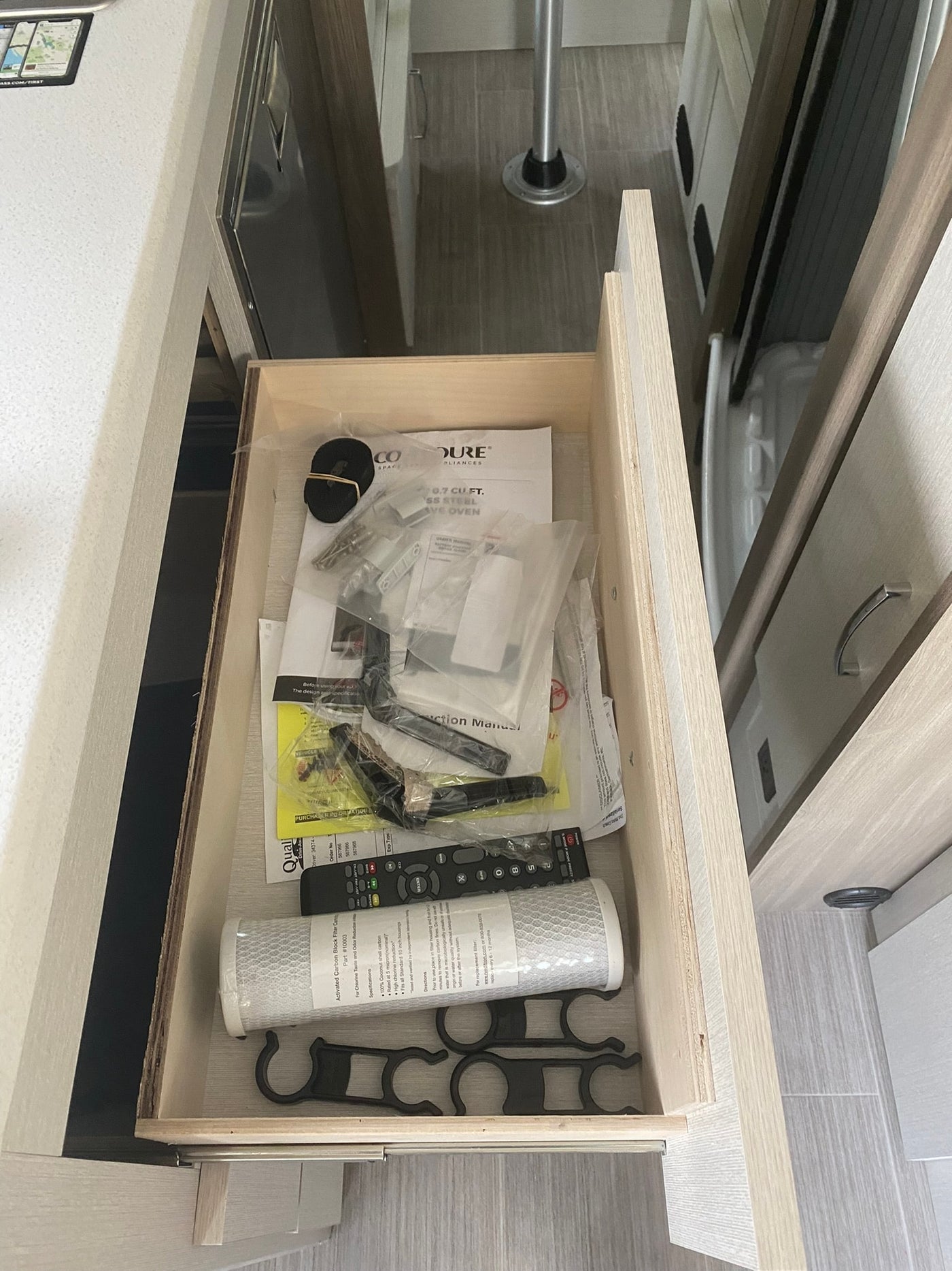 RV rental: Open drawer in modern RV interior with manuals, a water filter, remote control, and new appliance parts. — photo 16