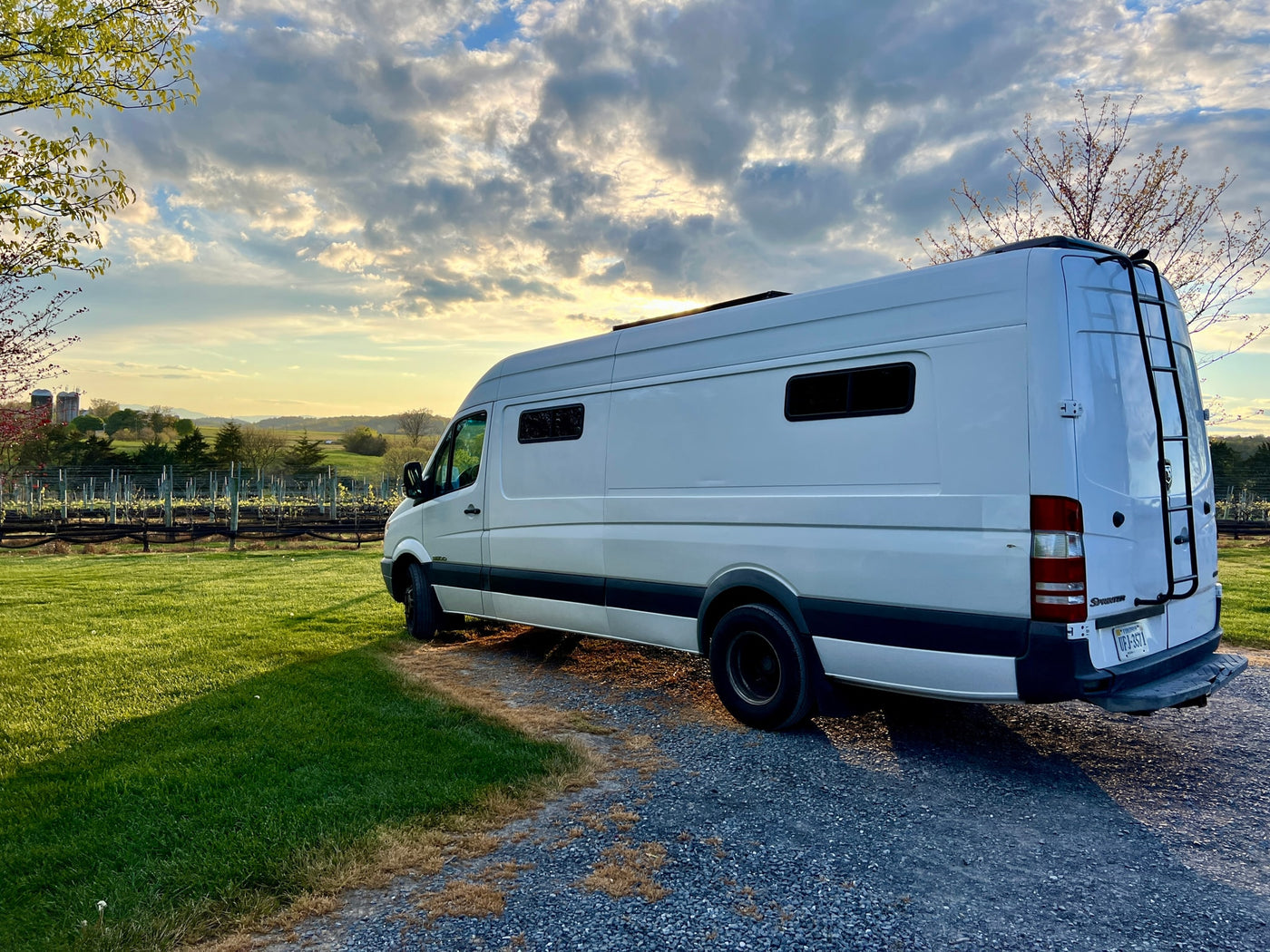 White Sprinter camper van, a perfect RV rental, parked at a picturesque vineyard during a golden sunset. — photo 9