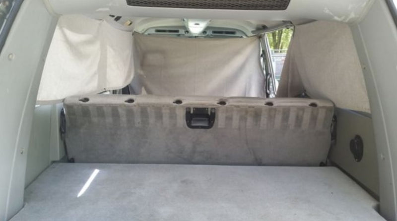 RV rental interior: A converted vehicle sleeping area with a gray bed base, seat back, and privacy curtains. — photo 5