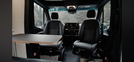 RV rental campervan interior with front seats & a side table, offering space for dining or remote work.