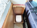 RV rental with a cleverly hidden Dometic portable toilet inside a wooden cabinet, located between a bed and a couch.
