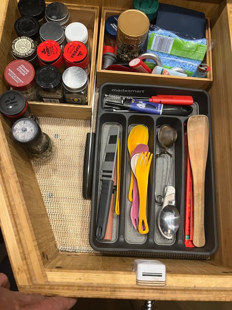 Organized kitchen drawer for an rv rental, featuring spices, MadeSmart utensil tray with colorful utensils, & cleaning sponge.