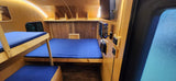 This RV rental's compact wooden interior features bunk beds, a main bed with blue cushions, LED lighting, and a TV setup.