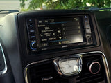 RV rental interior: infotainment system showing Sirius radio, navigation, and media options. Dashboard clock and phone mount visible.