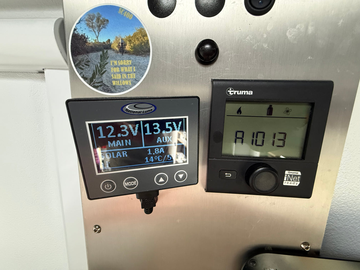 RV rental interior: National Luna battery monitor (12.3V main, 13.5V aux, 1.8A solar, 14°C) and Truma heating/hot water control panel.