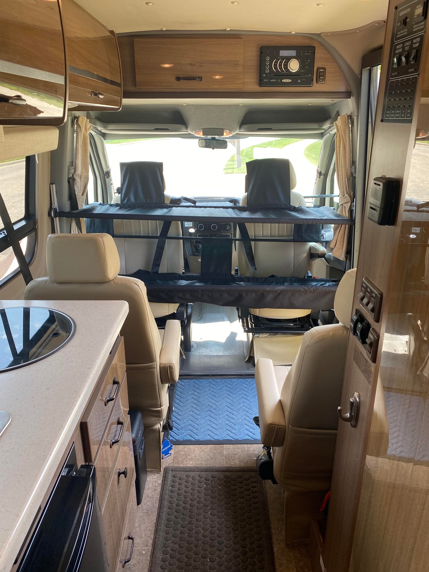 Spacious RV rental interior with cockpit view, kitchen counter, and pet barrier, ideal for road trips.