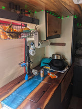 RV rental's cozy mobile kitchen: wood & resin countertop, fresh fruit, spices, cookware, and green lights.
