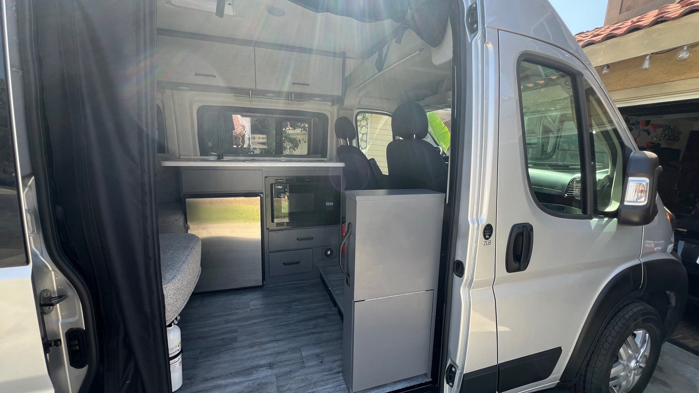 Modern RV rental interior showing kitchen, microwave, fridge, and seating area. Perfect for a cozy road trip.