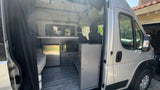 Modern RV rental interior showing kitchen, microwave, fridge, and seating area. Perfect for a cozy road trip.