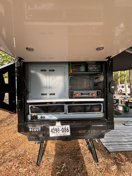 RV rental's compact outdoor kitchen with a Blackstone griddle, pull-out storage, and overhead lights for camping.