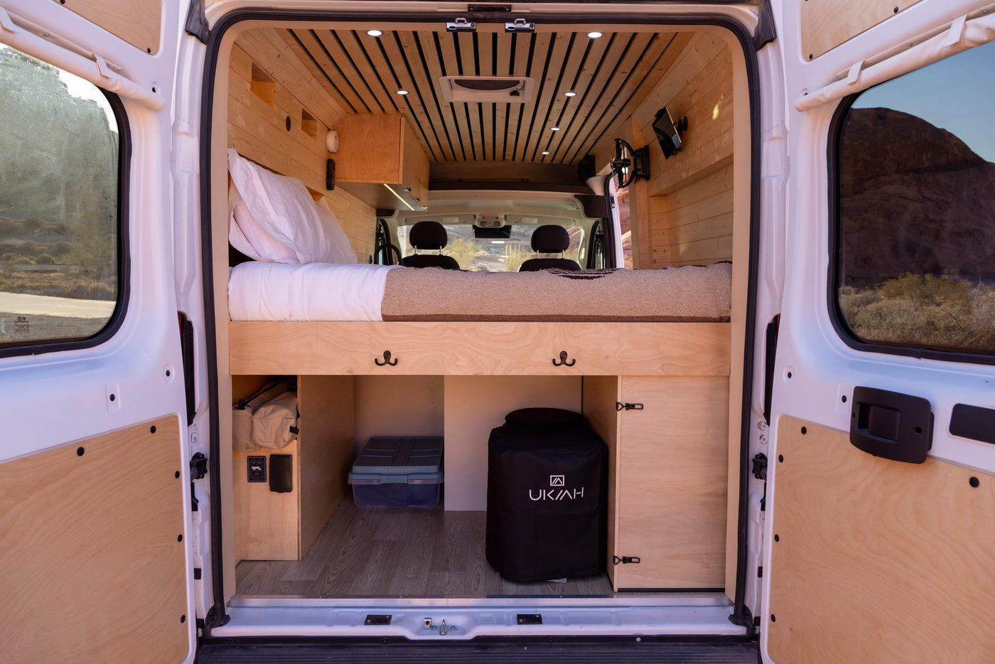 This RV rental's cozy, wood-paneled interior features a raised bed, storage, and visible front seats. Ideal for road trips. — photo 13