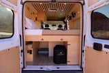 This RV rental's cozy, wood-paneled interior features a raised bed, storage, and visible front seats. Ideal for road trips.