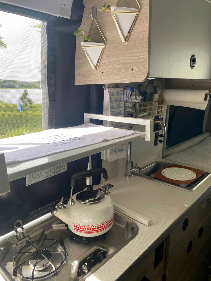 Compact RV rental kitchen with stove, sink, and lake view, perfect for camper adventures. — photo 10
