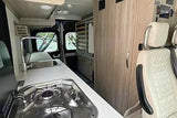 Modern RV rental interior: kitchen with sink & stove, ample storage, and comfortable front seats.