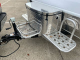 RV rental trailer's front hitch area, featuring a diamond plate storage box, steps, and crank jack.
