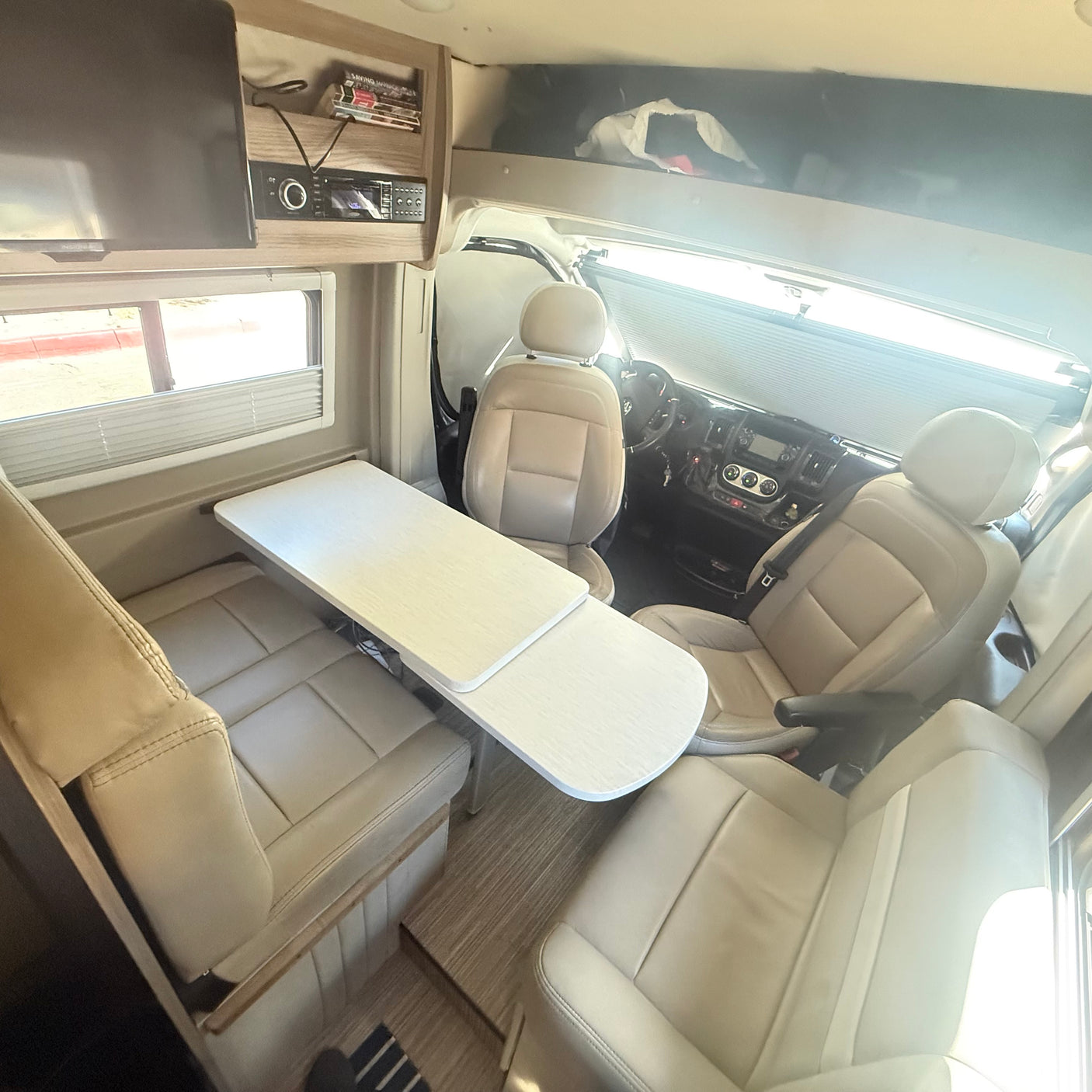 Comfortable rv rental interior: cream seating, dining table, and driver's cabin. Ideal camper living space.