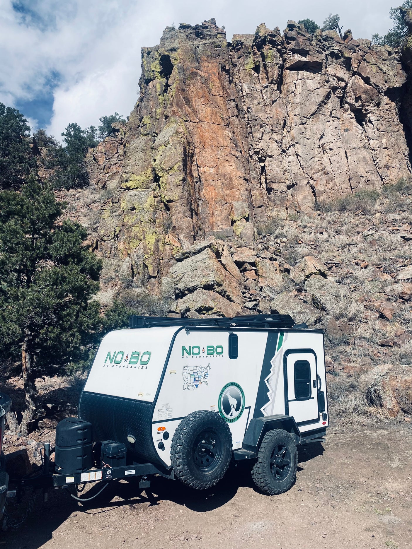 Adventure awaits with this rugged NO BO travel trailer RV rental, parked against towering rock cliffs.