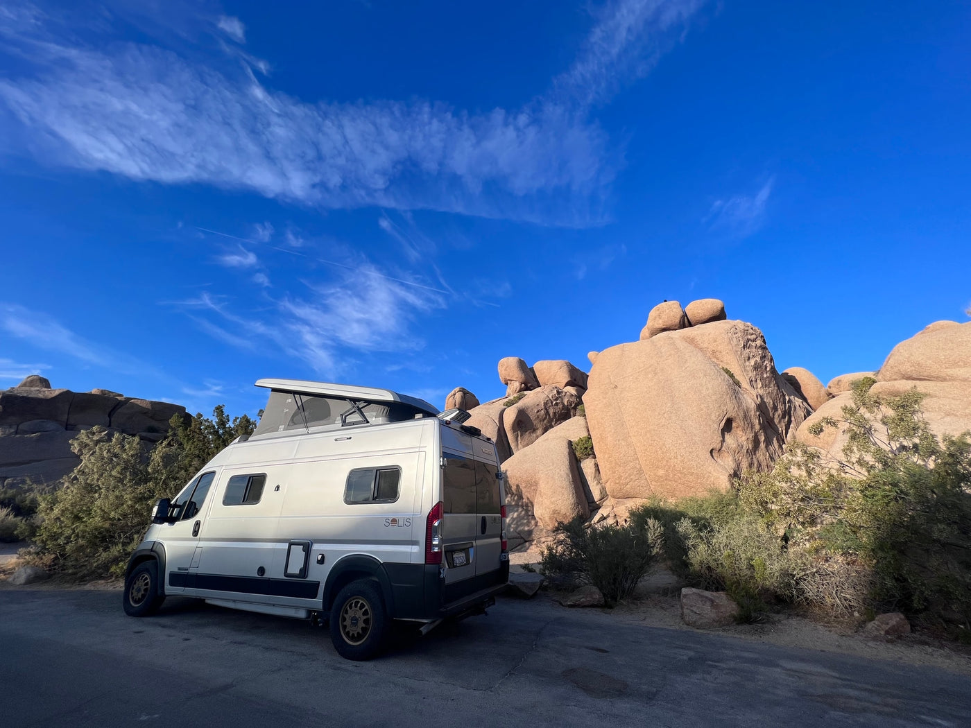Explore stunning landscapes! An RV rental camper van parked amidst iconic rock formations and desert plants under a clear blue sky. — photo 9