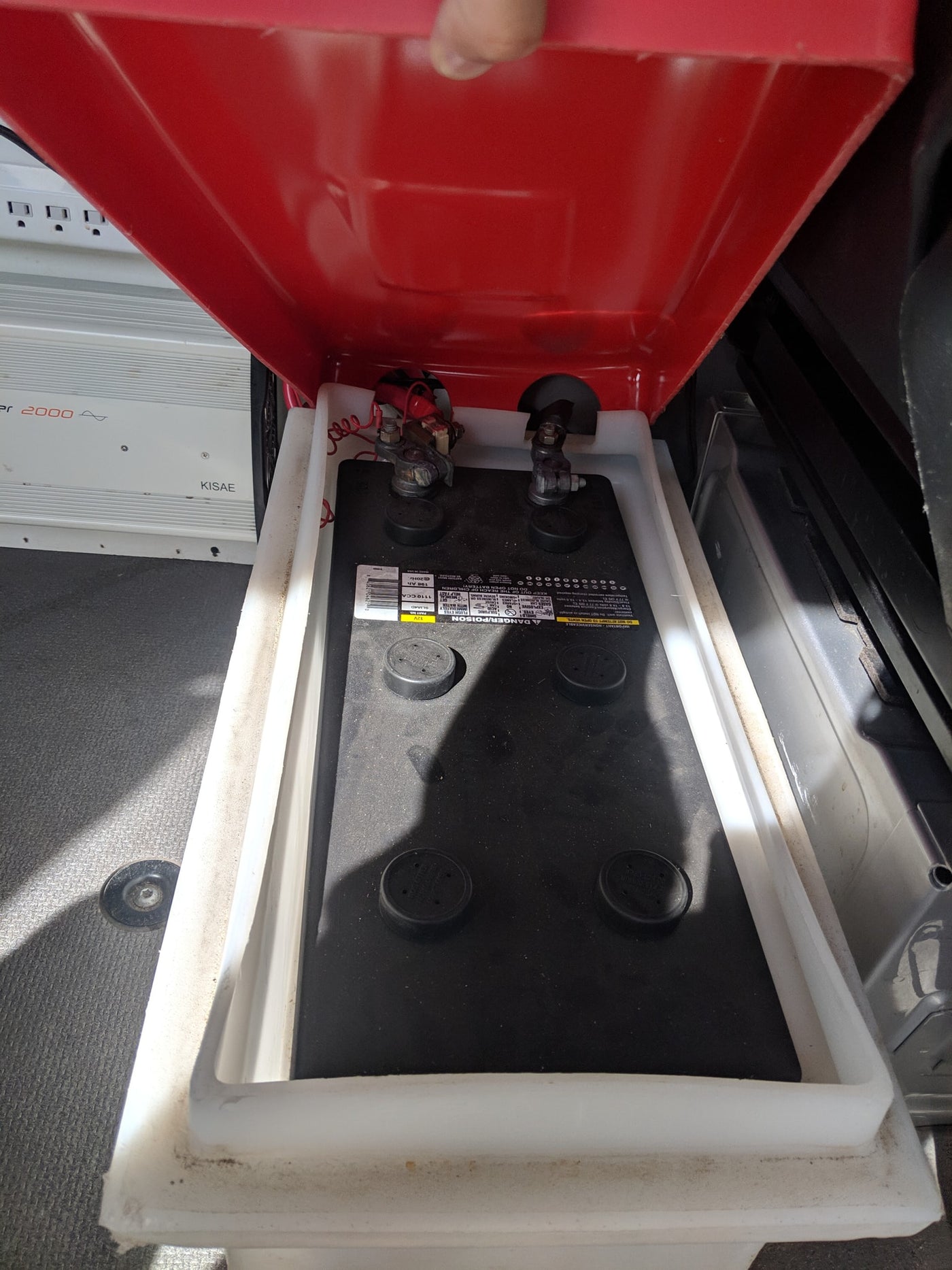 Inside an **rv rental**: A 12V deep cycle battery in its protective box, connected to a KISAE 2000W inverter for off-grid power. — photo 38