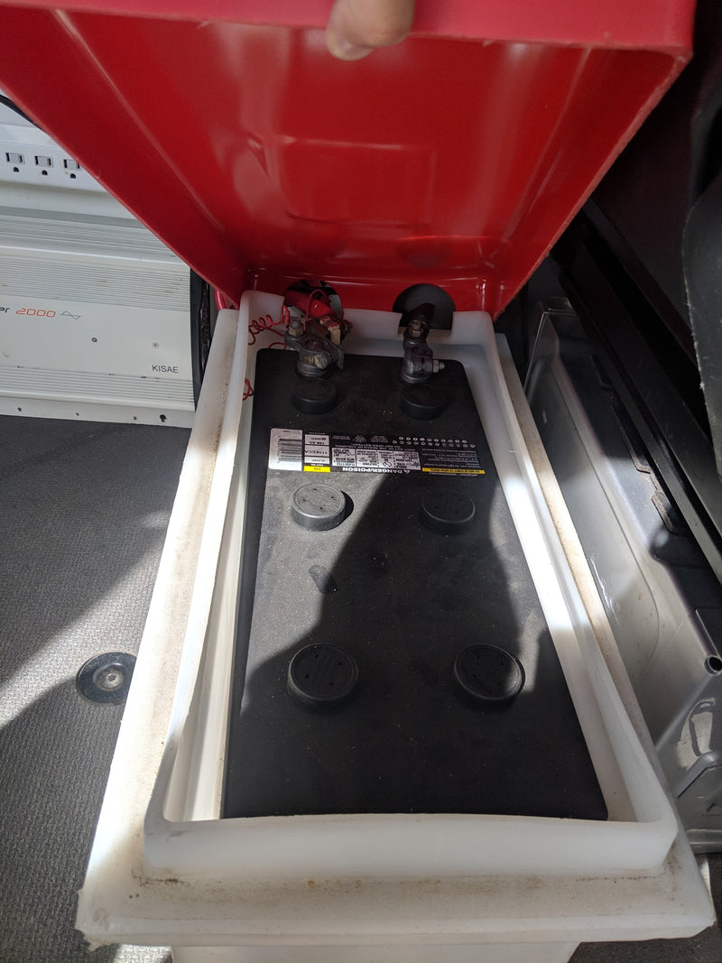 Inside an **rv rental**: A 12V deep cycle battery in its protective box, connected to a KISAE 2000W inverter for off-grid power. — photo 38