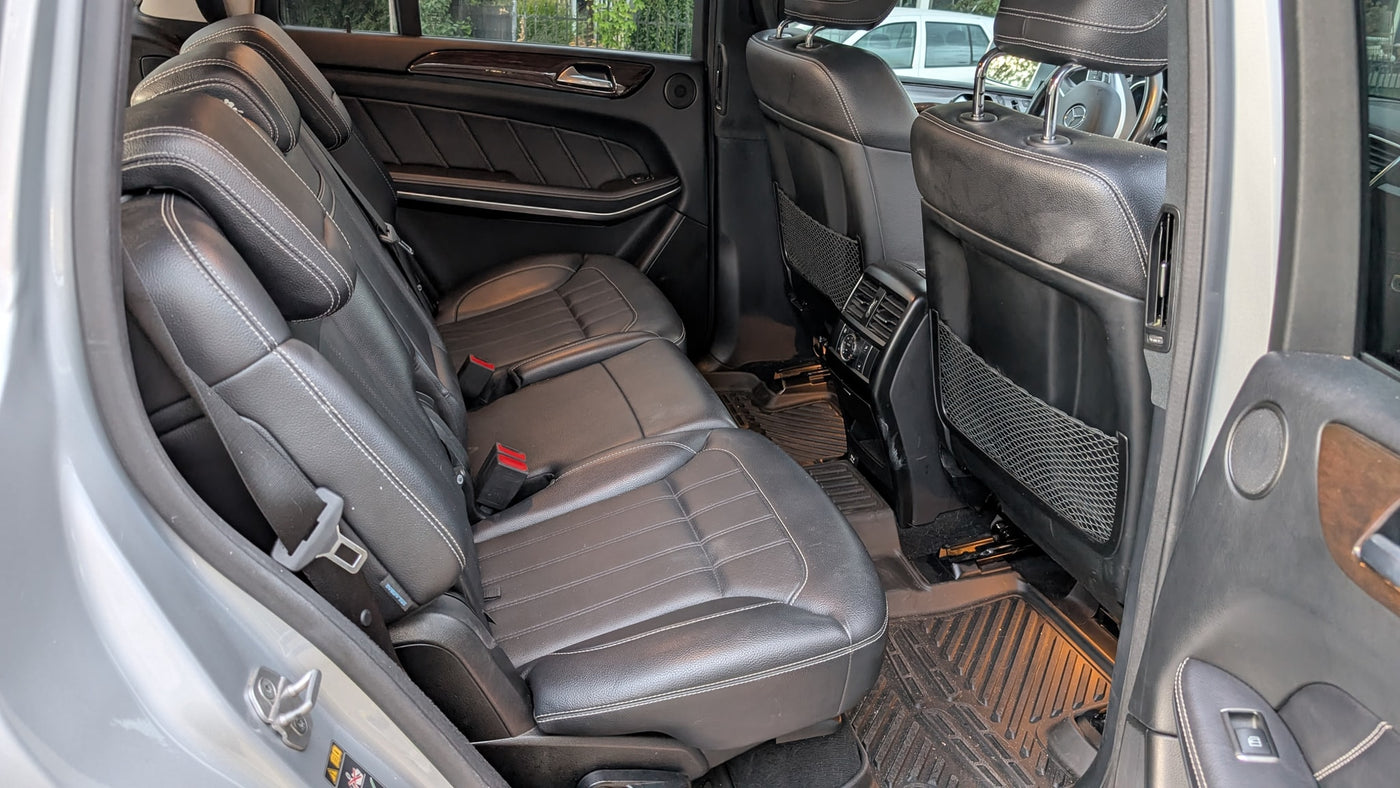 Roomy vehicle interior for your RV rental journey, showing black leather rear seats with white stitching and durable floor mats. — photo 9