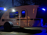 A sleek Luna Rover travel trailer glows with blue and white lights at night, ready for your next RV rental journey.