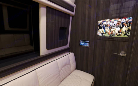 Relax in this RV rental's luxury interior, featuring white quilted seating, a flat-screen TV, and smart controls.