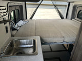 Explore a comfortable RV rental! Features a spacious bed, functional kitchen sink, and clever storage solutions.