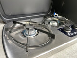 This two-burner portable gas stove, with one burner lit, is perfect for cooking on an RV rental trip.
