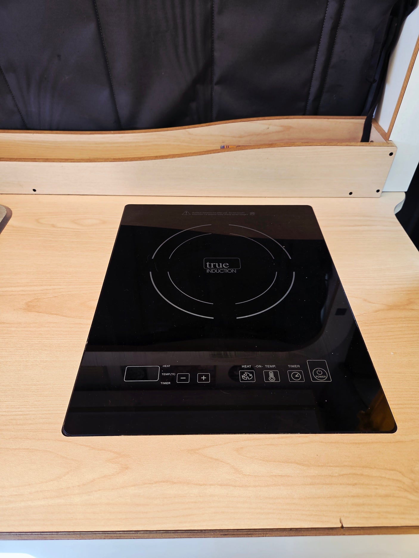 Black built-in induction cooktop in an RV rental kitchen, with touch controls for heat, temperature, and timer settings.