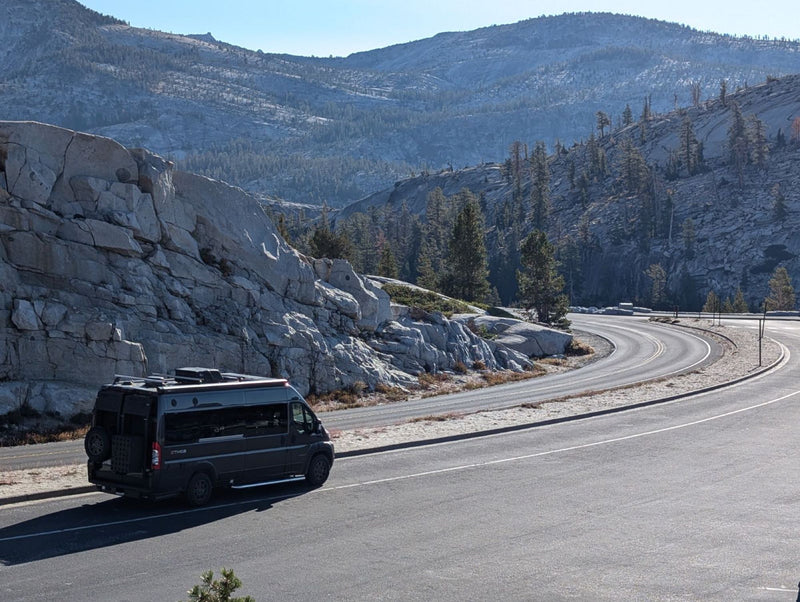 Dark RV rental camper van parked on a winding mountain road — photo 1