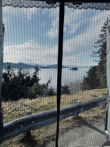 Scenic view from an RV rental: a bay, mountains, and trees, beautifully framed by a mesh screen from inside.