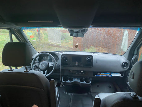 Inside a Mercedes RV rental: dashboard, steering wheel, and travel guides on the passenger side shelf, ready for adventure.