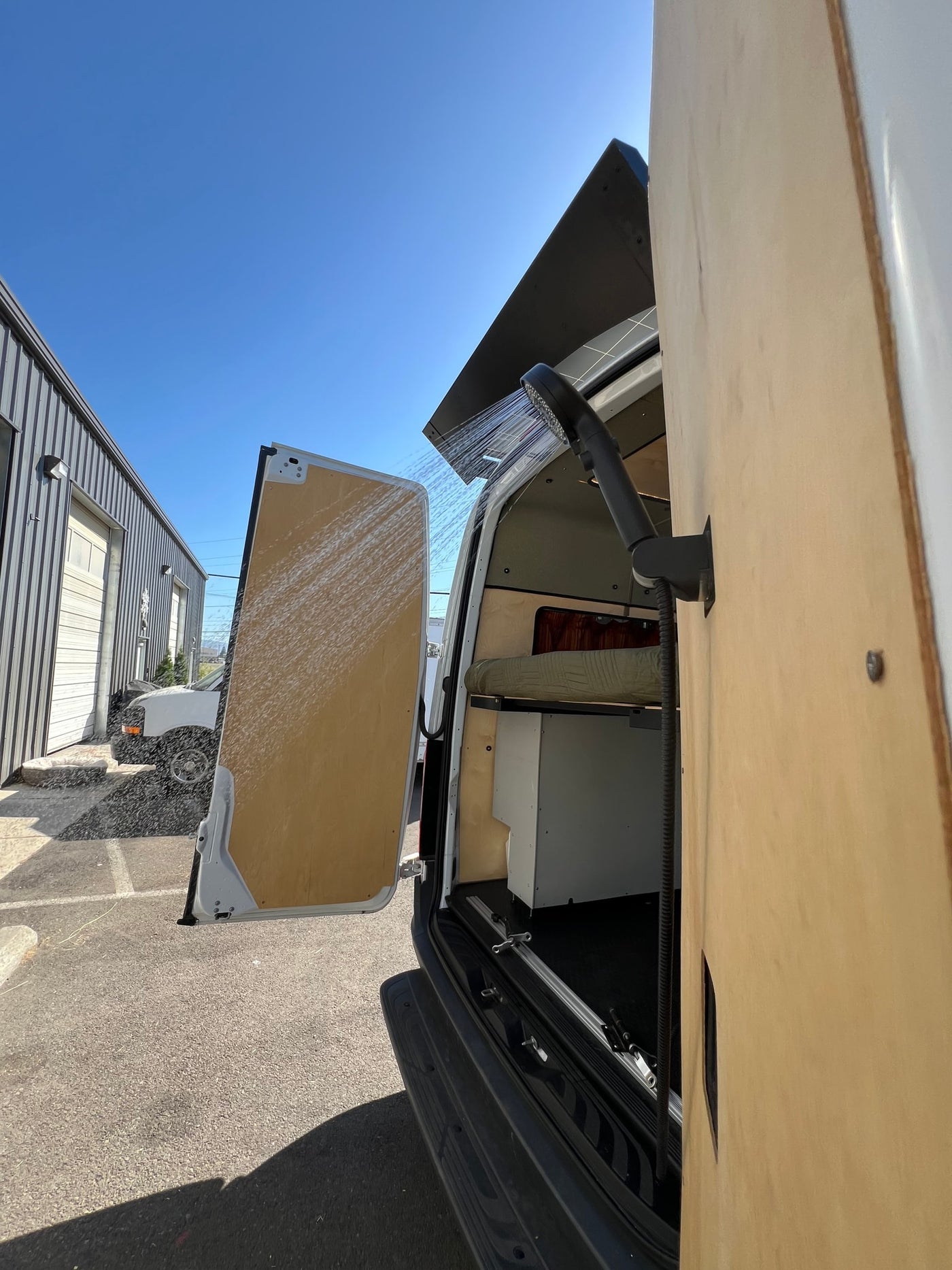RV rental camper van offers an outdoor shower. Water sprays from the rear, showing mobile living convenience. — photo 3