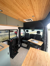 Modern rv rental camper van interior: bamboo ceiling, custom cabinets, and a clever passenger seat desk for remote work.