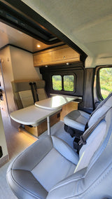 Spacious rv rental interior featuring a dining table with two rear seats, two swiveling front seats, and large windows.