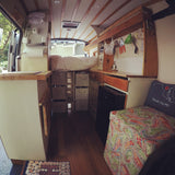 Explore this unique rv rental: a cozy camper van interior with an elevated bed, efficient kitchen, smart storage, and vibrant seating.