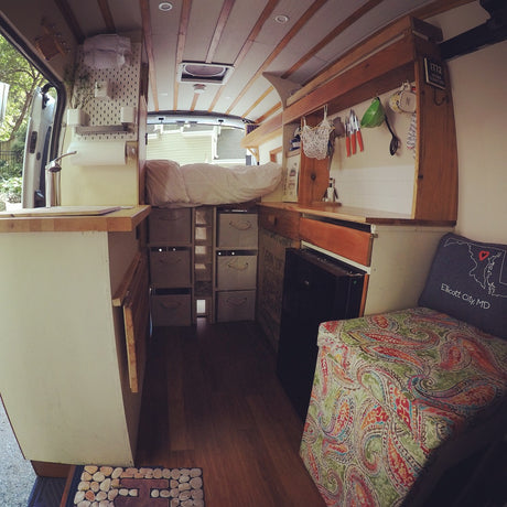 Explore this unique rv rental: a cozy camper van interior with an elevated bed, efficient kitchen, smart storage, and vibrant seating.