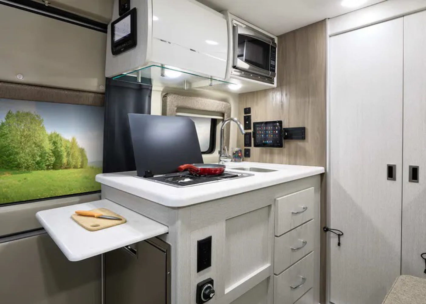  parked on asphalt under a clear blue sky.|Dark grey Ram ProMaster RV rental parked outdoors under a clear blue sky. Ready for your next adventure.|RV rental's modern mobile living space: compact kitchen — photo 10