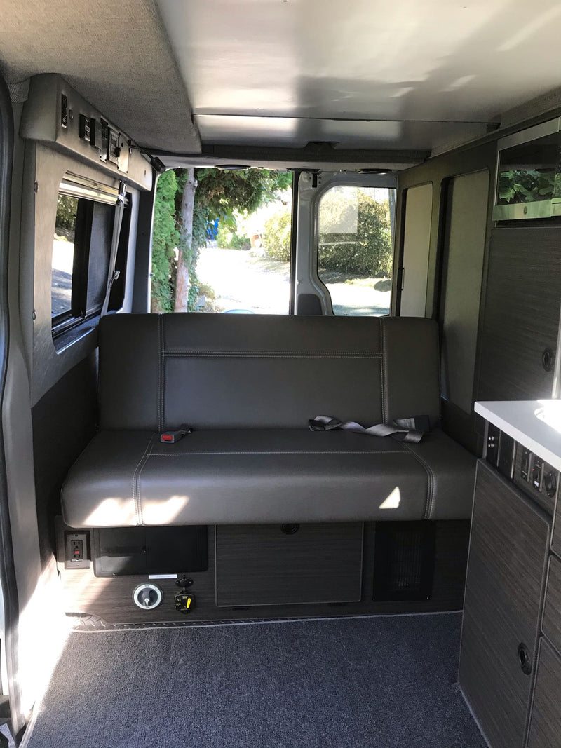  & comfy seating area.|Explore this RV rental's comfortable and modular camper van interior. Features include a convertible bed & storage.|Inside this modern **rv rental**: a comfortable bench seat — photo 7