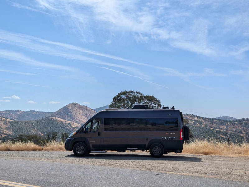  equipped for off-road rv rental. Features roof rack & rear gear carrier.|Thor Ethos camper van parked on a scenic mountain road. This dark grey RV rental is ready for adventure!|Spacious RV rental interior with modern kitchen — photo 2