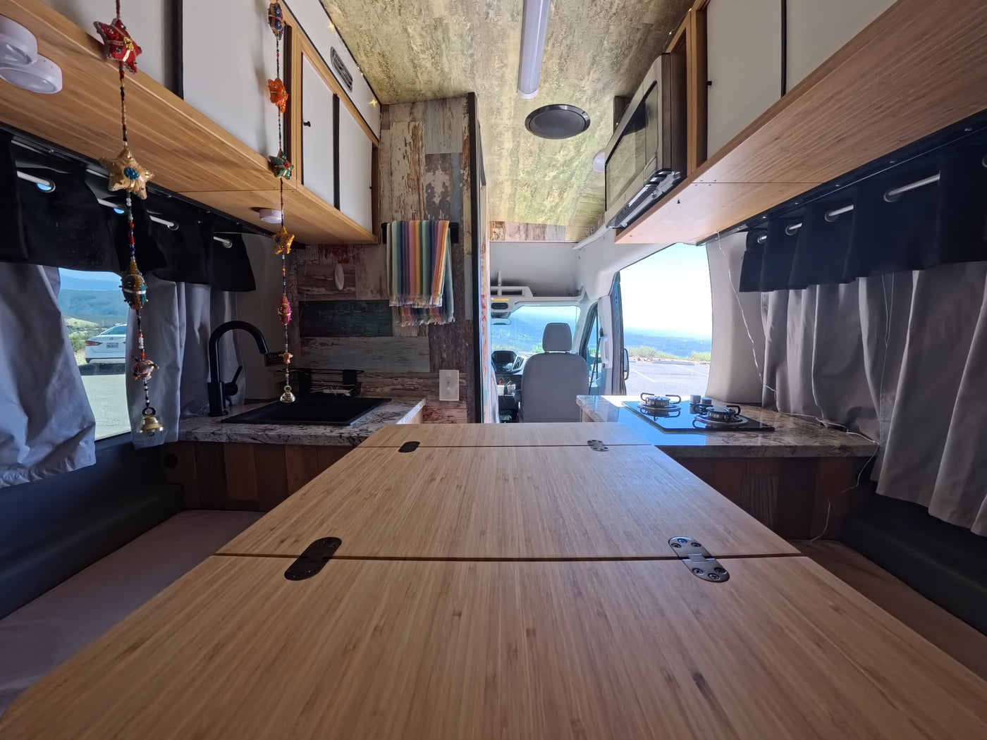  parked with mountain views.|Black camper van RV rental with open door — photo 11