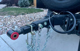 RV rental ready: A trailer hitch receiver with red bushing, attached safety chains, and partial spare tire for towing.